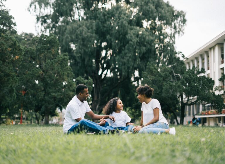 Happy Black family enjoying quality time together outdoors in a lush green park, symbolizing family connection and joy Therapy for parents in Blaine MN
