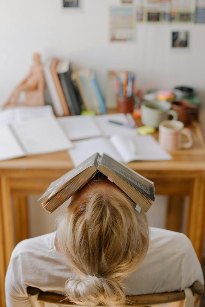 Student looking stressed with a book covering her face, symbolizing academic stress and overwhelm Therapy for Academic Stress in Blaine MN