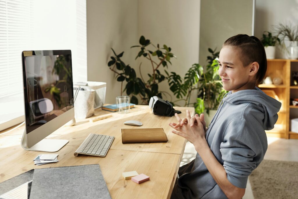 Teenage boy sitting at his desk, watching the screen of his computer, symbolizing focus, learning, and technology use Therapy for Academic Stress in Blaine MN