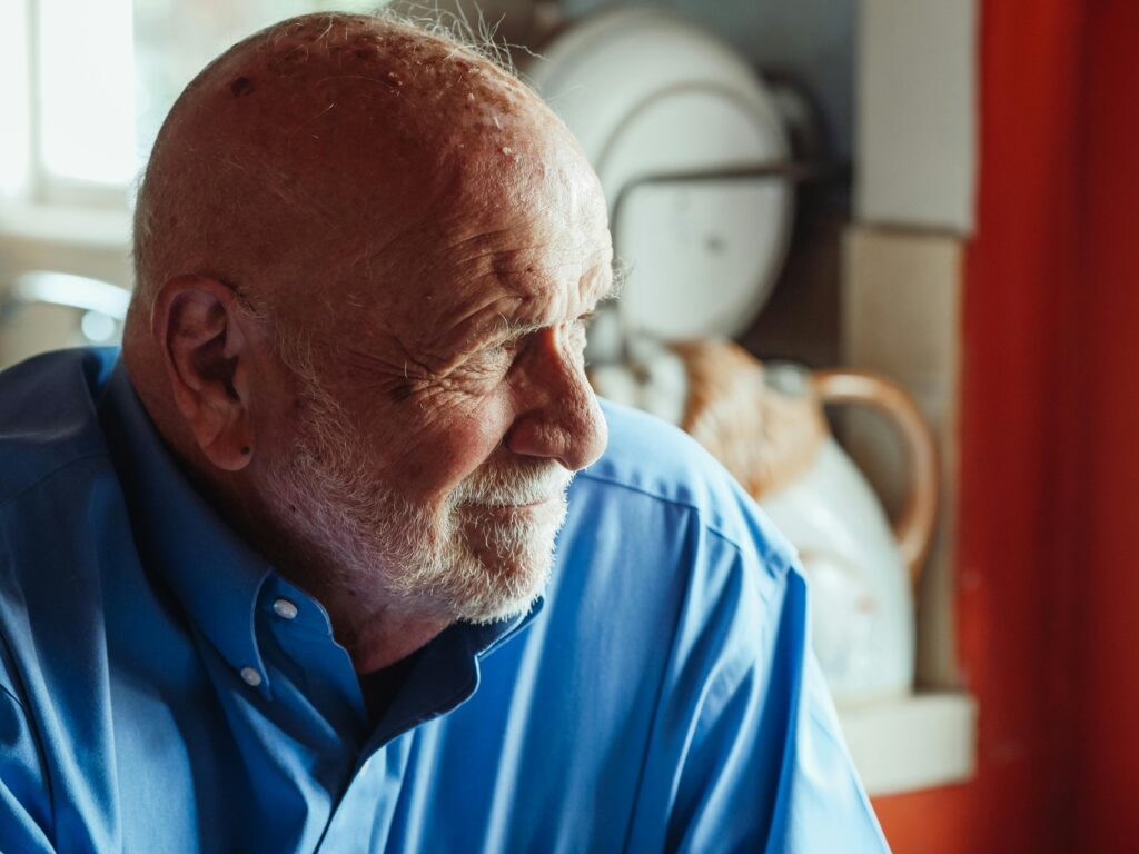 Portrait of a senior man wearing a blue shirt and beard, captured in a cozy indoor setting. Therapy for adults in blaine MN.