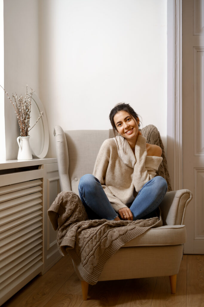 Woman sitting on a chair by a window, looking very calm. Therapy for trauma in Blaine Mn