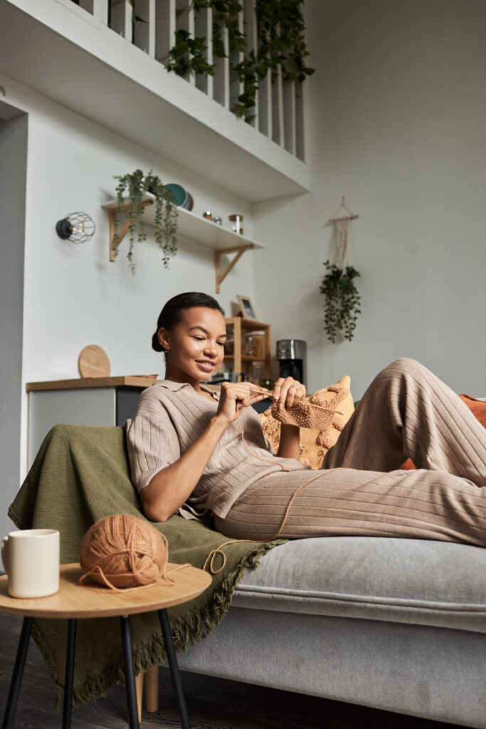 Young woman knitting on a couch. Therapy for trauma in Blaine MN