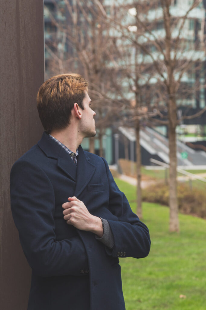 Counseling for recovery in Blaine MN. Young man standing next to a tree, watching something