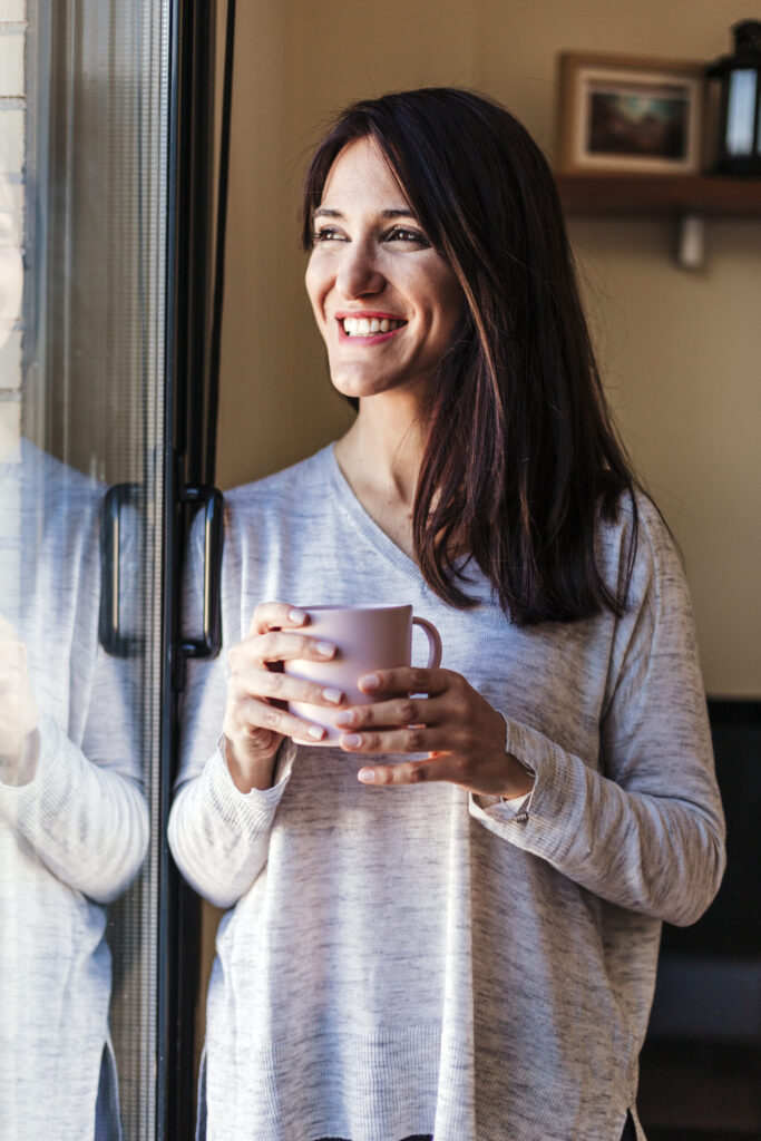 Therapy in Blaine MN . Woman standing by door, drinking a cup of tea.
