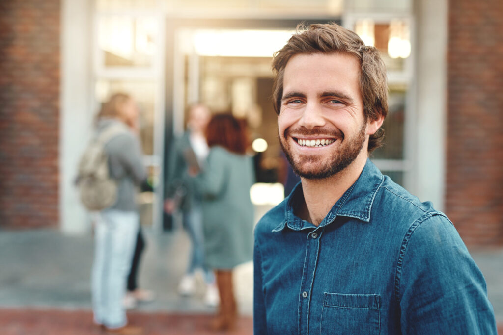 Therapy for self esteem in blaine mn . Young man smiling against a brick building.