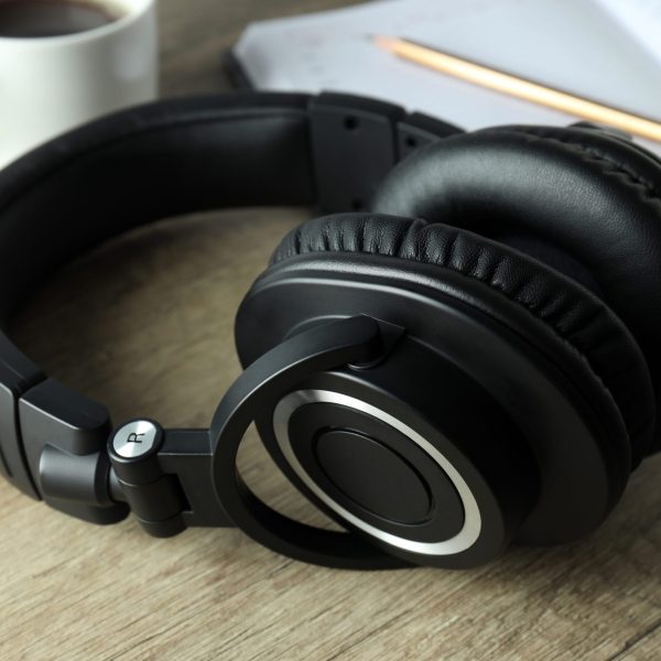 Black big headphones, on a table with a notebook and coffee.