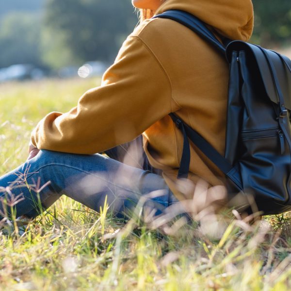 Closeup image of a female traveler with backpack sitting in the park