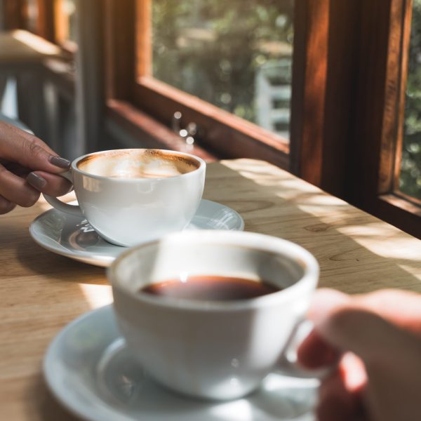 Closeup image of two people holding and drinking coffee in the morning
