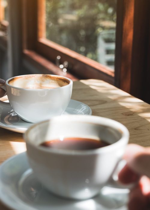 Closeup image of two people holding and drinking coffee in the morning