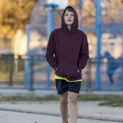 Front view of a young hooded teen male walking away