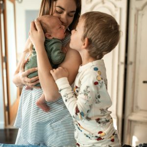 Mother holding her newborn baby while the older brother looks face-to-face with the baby, symbolizing family bonding, love, and sibling connection. Therapy For Life Transitions In Blaine MN Therapy services in Blaine MN Therapy in Blaine MN