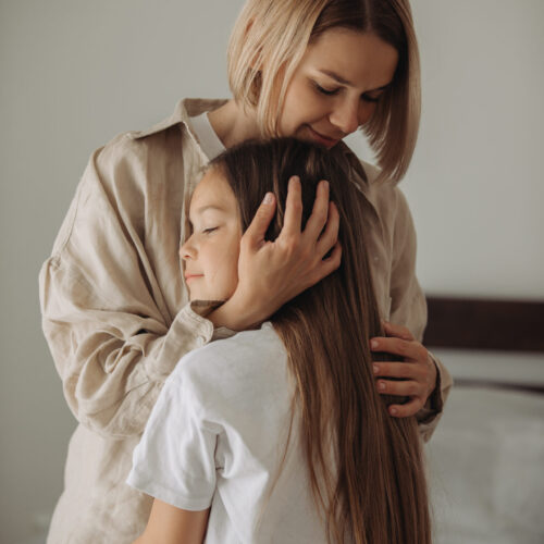 Mother hugging her daughter with daughter's back turned. Therapy for children in blaine mn