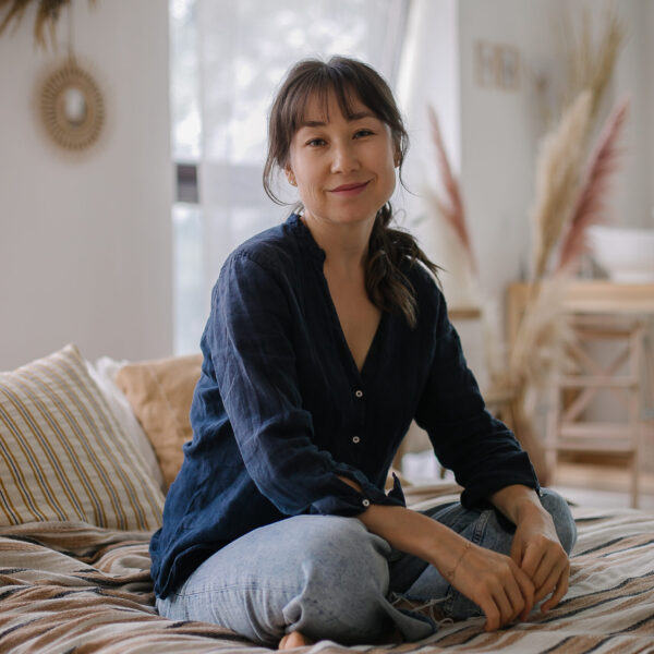 Portrait of beautiful Asian young brunette woman sitting on bed. Concept of do
