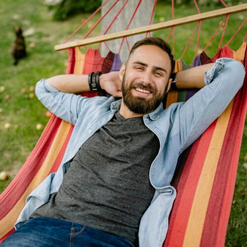 White man with a goatee lying in a hammock, smiling, symbolizing relaxation and leisure Therapy for adults in Blaine MN