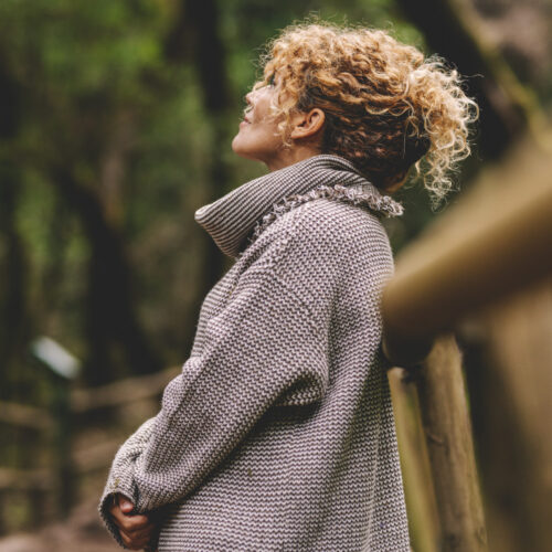 Side portrait of woman relaxing in the nature. Inner balance and mindfulness concept moments. Standing female people in the woods enjoying silence and good nature vibes alone smiling and admiring